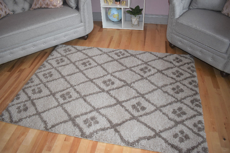 Patterned rug on a wooden floor with gray sofa and white shelf in the background
