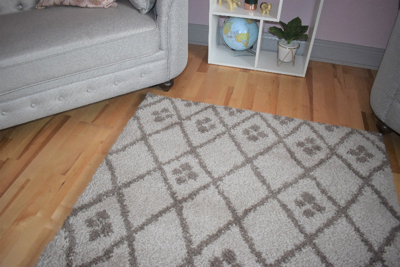 Patterned rug on a wooden floor with a gray sofa and small shelf in the background.