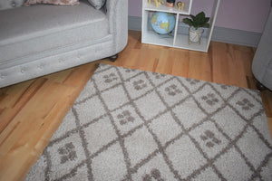 Patterned rug on a wooden floor with a gray sofa and small shelf in the background.