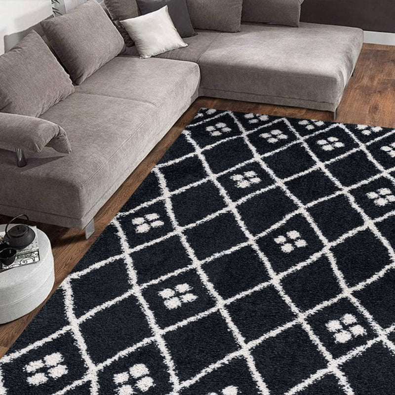 Grey sectional sofa with a black and white patterned rug in a living room setting.