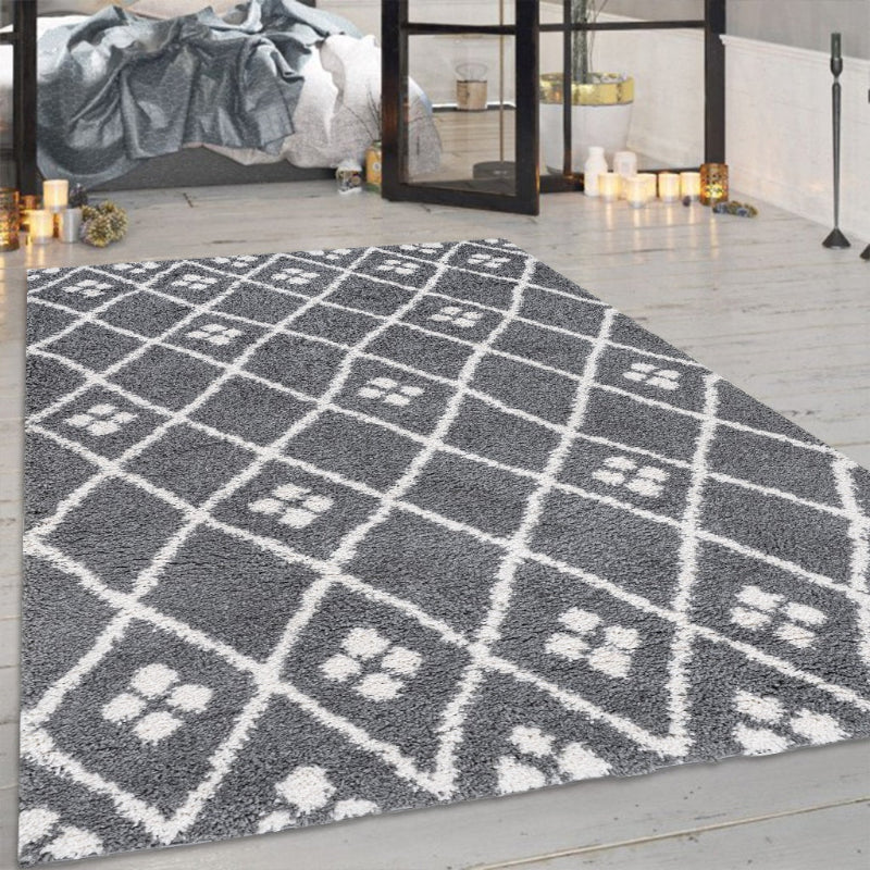 Grey geometric patterned rug on a wooden floor with a bedroom in the background.