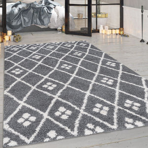Grey geometric patterned rug on a wooden floor with a bedroom in the background.