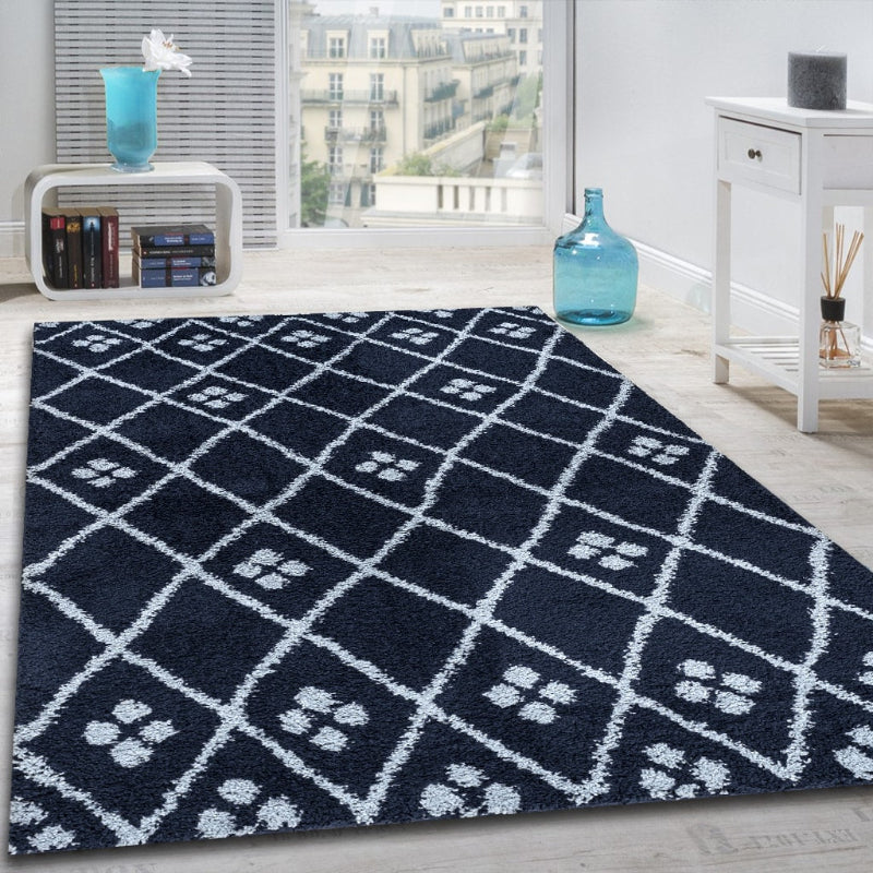 Navy blue geometric patterned rug in a room with white walls and furniture.