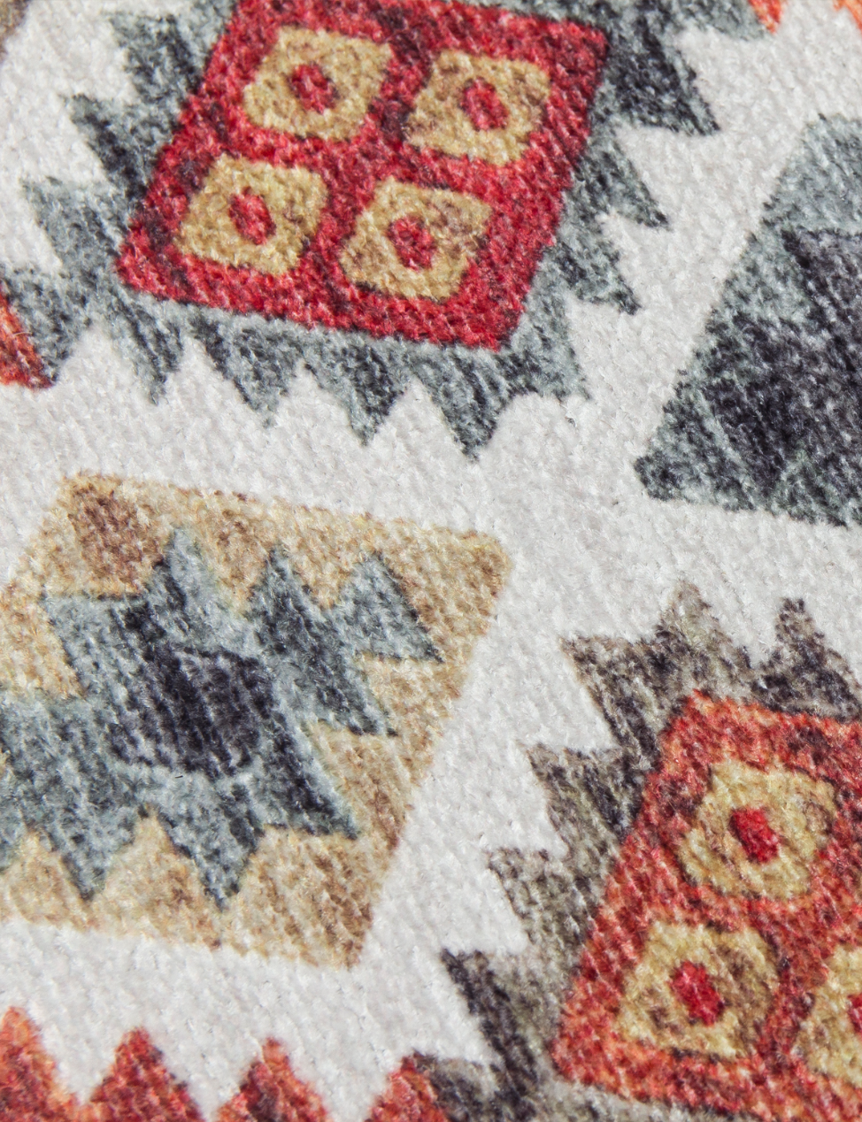 Close-up of a textured fabric with geometric pattern featuring red, beige, and gray colors.