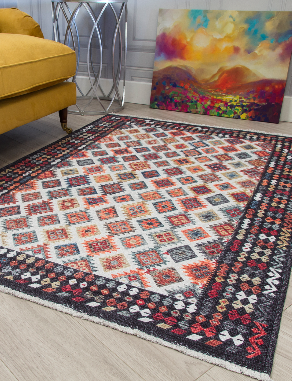 Patterned rug on a wooden floor with a yellow sofa and colorful painting in the background.