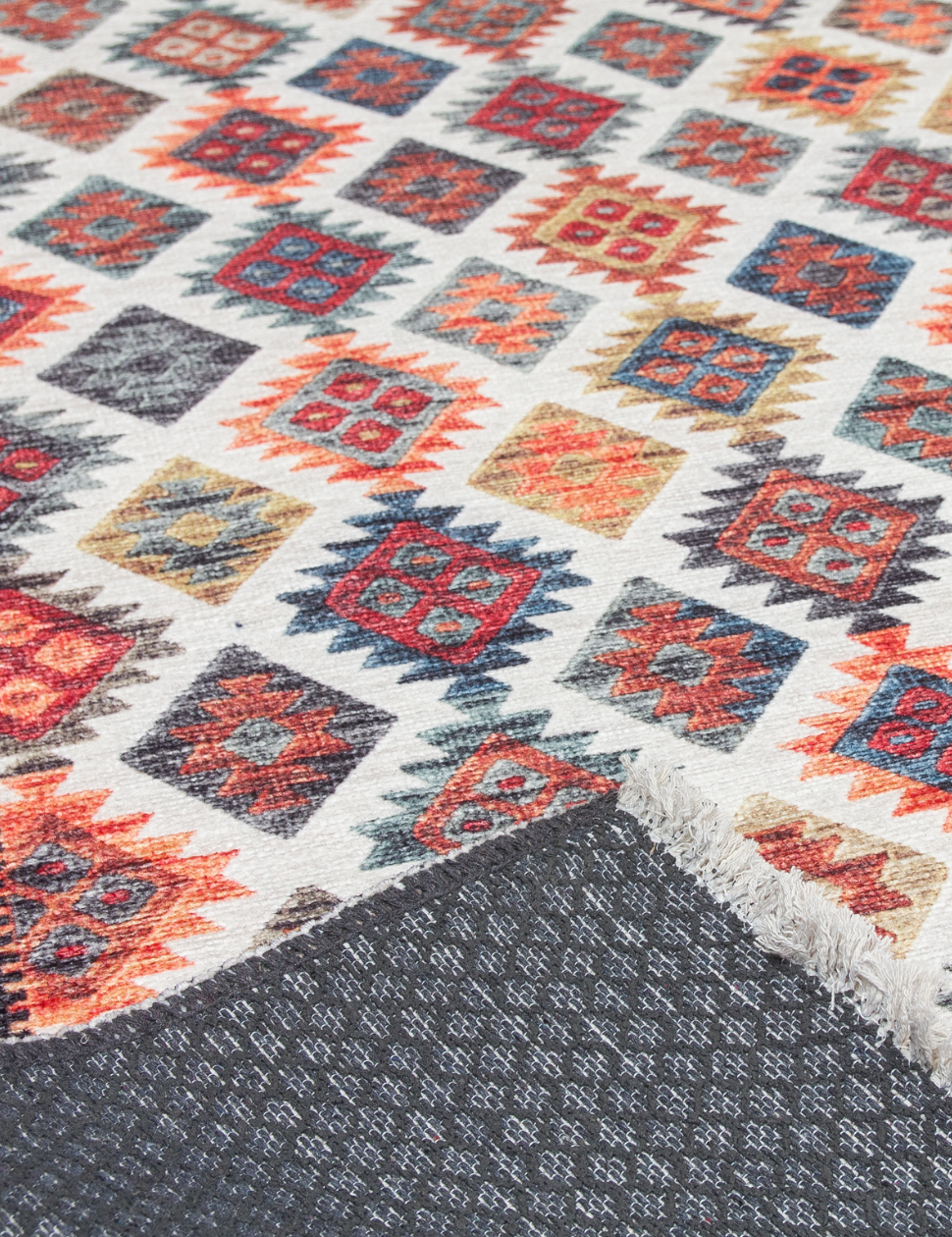 Close-up of a patterned rug with geometric designs in red, blue, and orange on a white background.