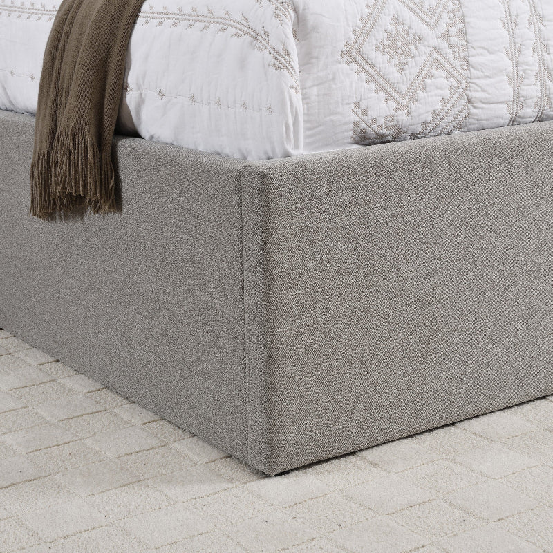 Gray upholstered bed frame with a textured finish on a light stone floor.