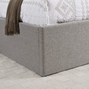 Gray upholstered bed frame with a textured finish on a light stone floor.
