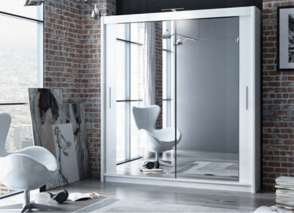 Modern white wardrobe with mirror doors in a room with brick walls and a chair.