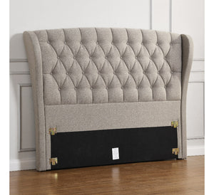 Gray tufted headboard with wingback design on a wooden floor.