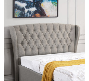 Gray tufted headboard with a bed and yellow blanket in a bedroom setting.