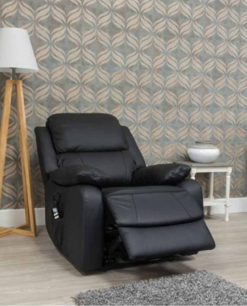 Black leather recliner chair in a room with patterned wallpaper and a lamp.