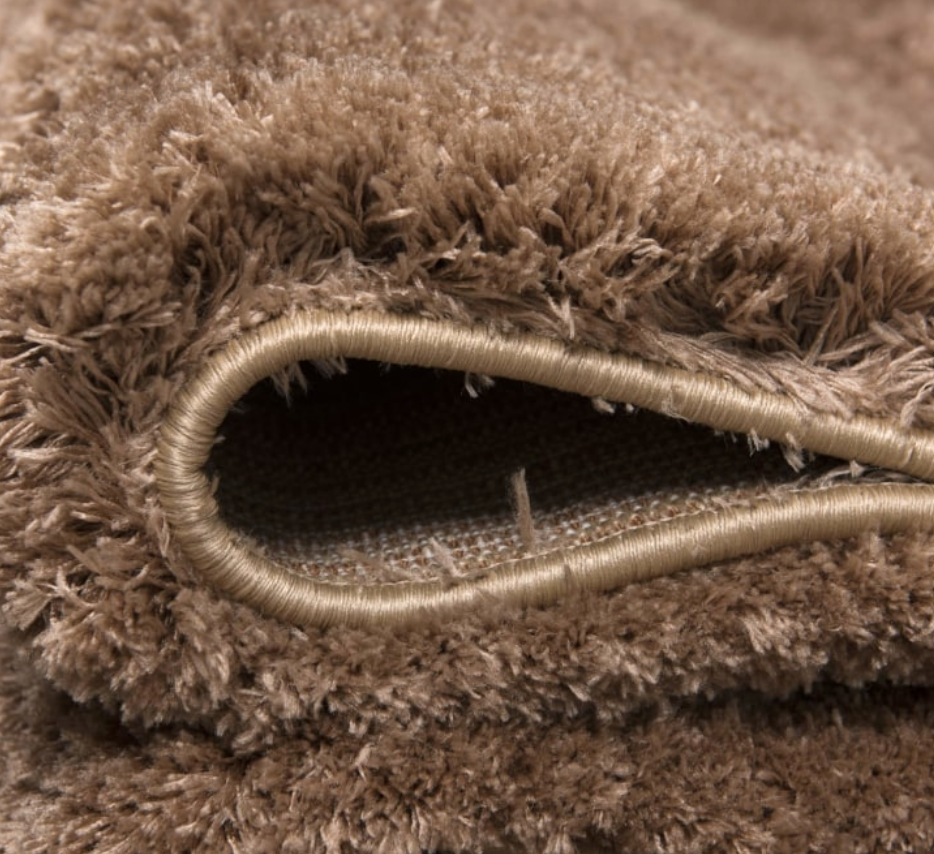 Close-up of a brown shaggy rug with visible texture and edges.