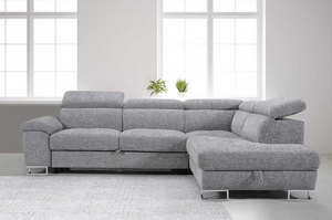 Gray sectional sofa in a room with large windows and plants.