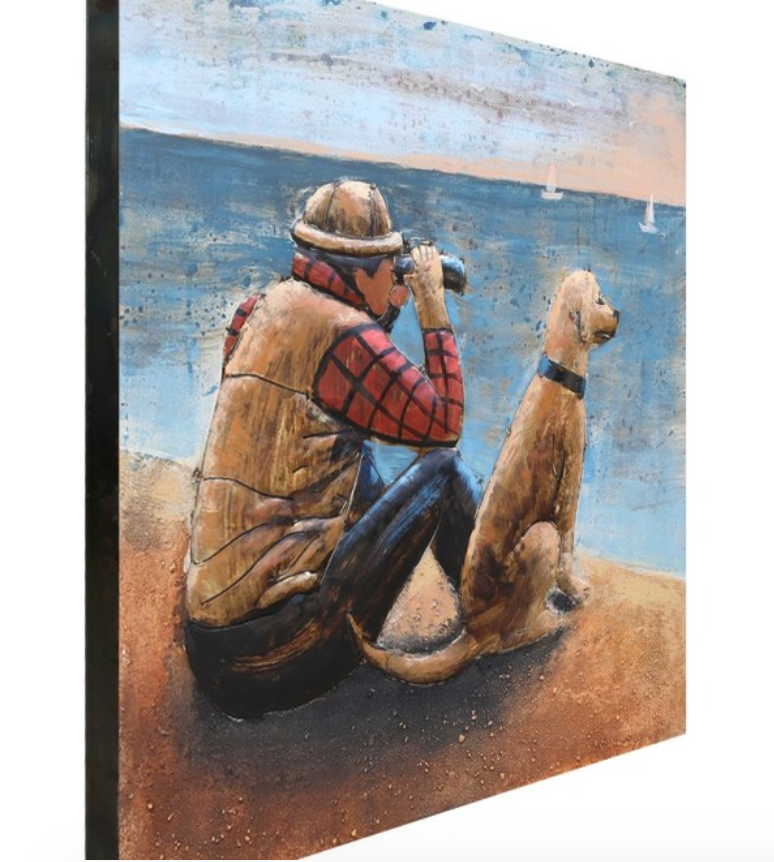 Wooden sculpture of a person with a dog on a beach
