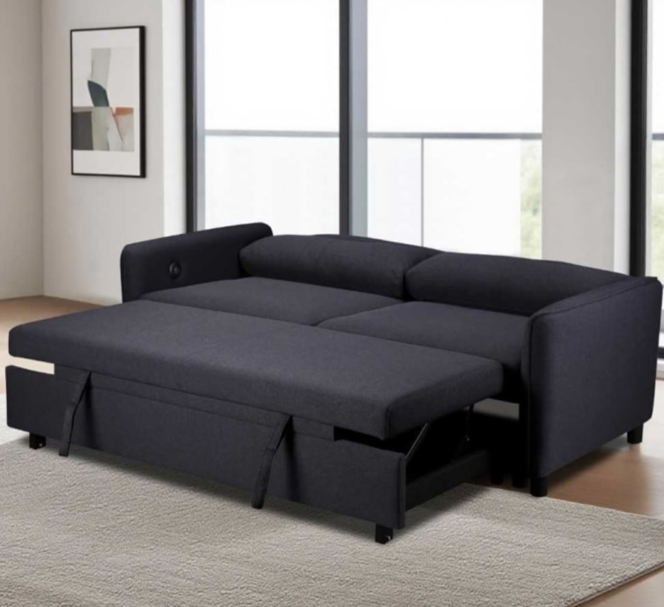 Black sectional sofa with pull-out bed in a room with large windows.