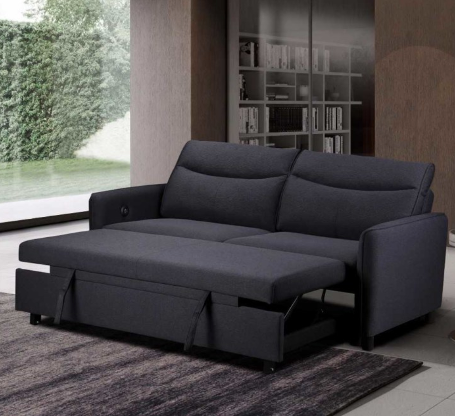 Dark gray sectional sofa with pull-out bed in a room with bookshelf and window.