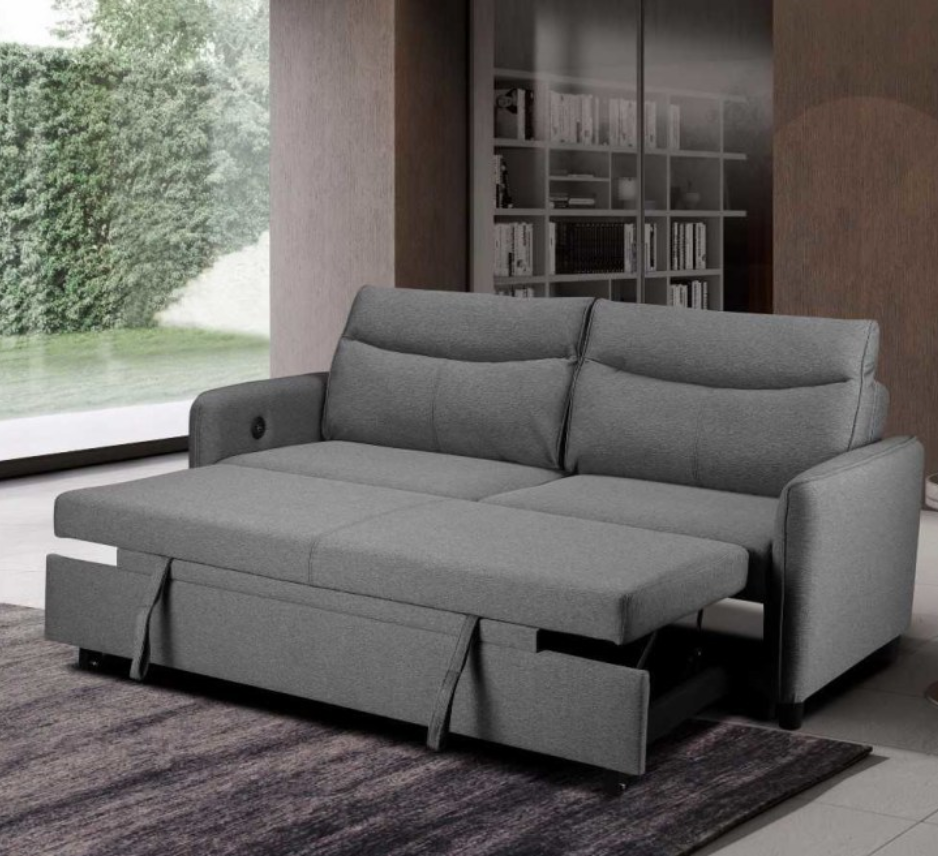 Gray sofa bed in a living room setting with a bookshelf in the background.