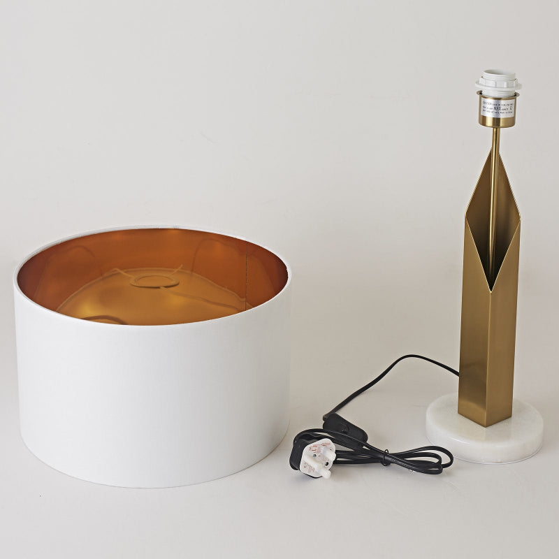 Modern lamp with white base, gold interior, and marble accent on a light gray background