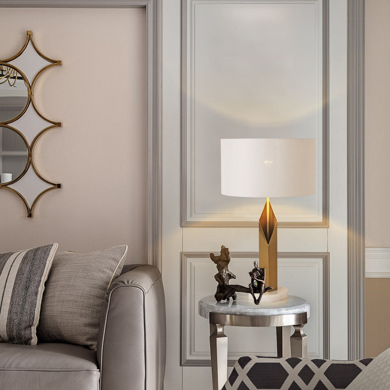 Modern living room with a sofa, decorative mirror, and side table with a lamp.