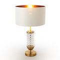 Table lamp with a white shade, gold base, and crystal accents on a white background