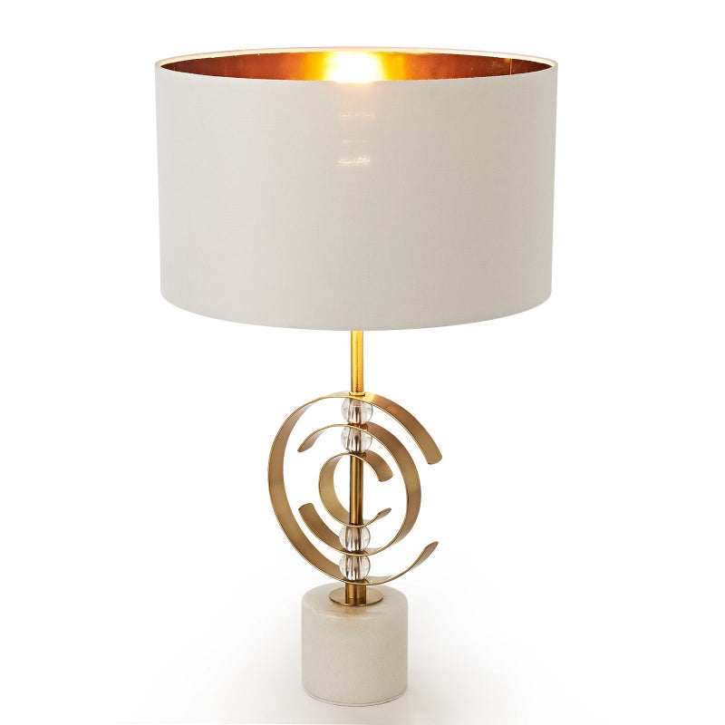 Table lamp with a white shade and gold base on a white background