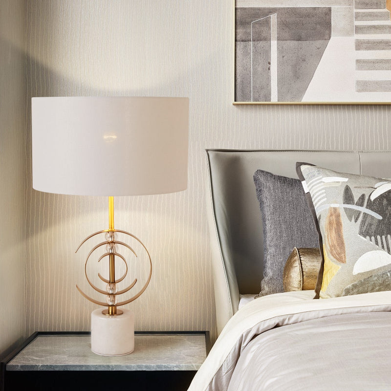 Modern bedroom with a lamp on a nightstand and a bed with decorative pillows.