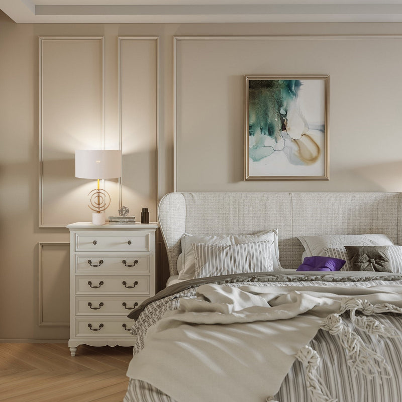 Neatly made bed in a bedroom with a side table and wall art.
