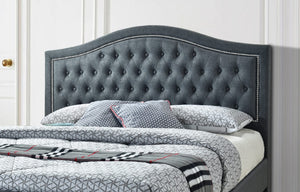 Grey tufted headboard with bedding and pillows on a bed.