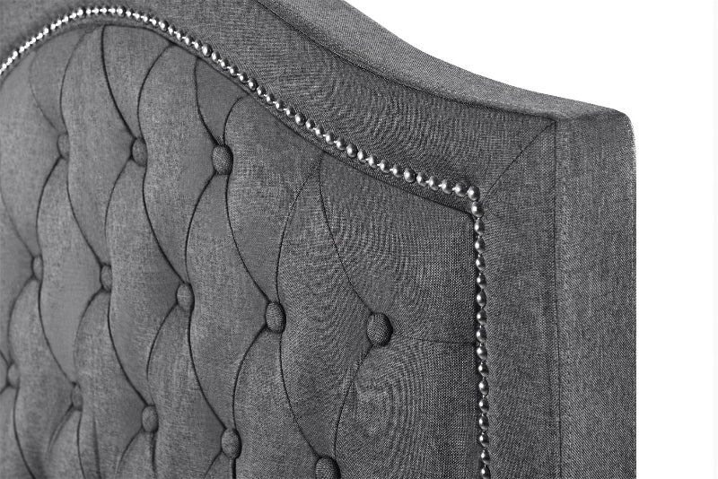 Grey tufted headboard with decorative stitching on a white background