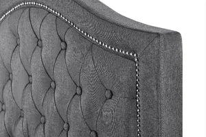 Grey tufted headboard with decorative stitching on a white background