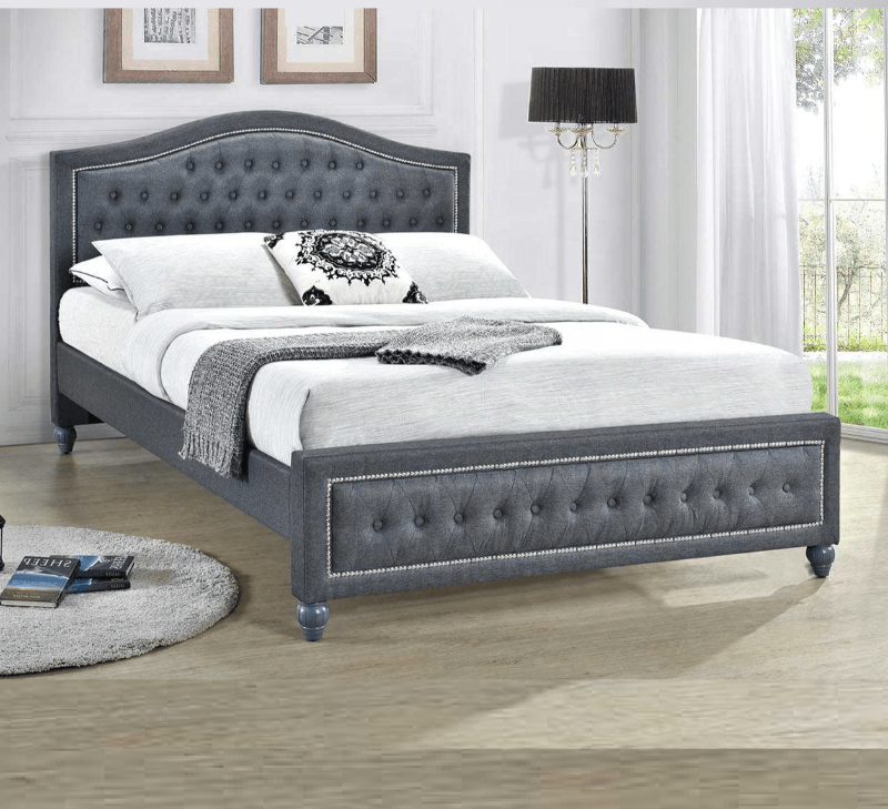 Grey upholstered bed in a bedroom setting with white bedding and decor.