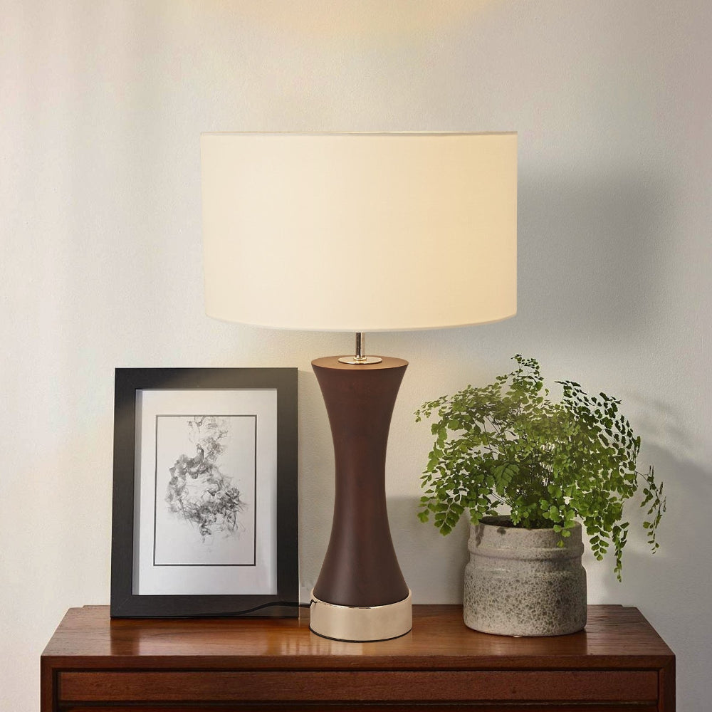 Decorative lamp on a wooden surface with a plant and framed picture in the background