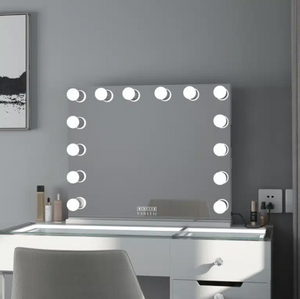 Makeup vanity with a mirror with lights on a gray wall.