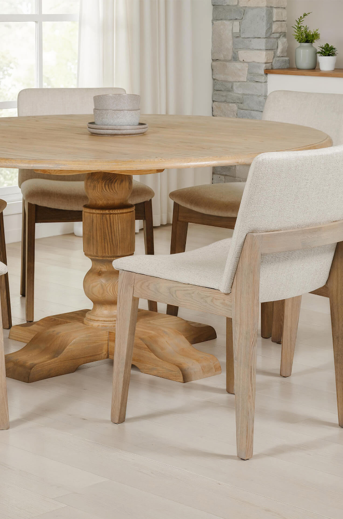 Wooden dining table with chairs in a bright room with large windows.