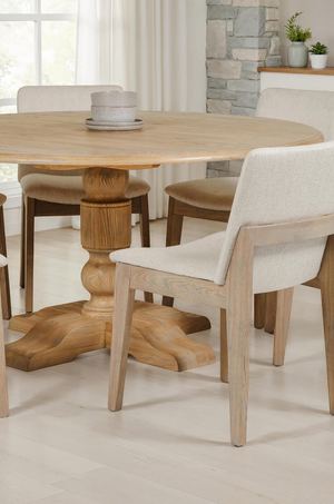 Wooden dining table with chairs in a bright room with large windows.