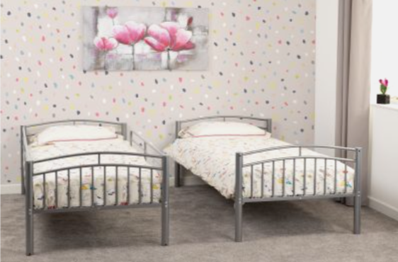 Two metal beds with white bedding against a polka dot wall.