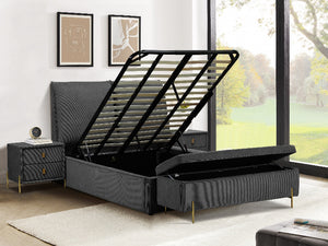 Grey upholstered bed with open storage drawers in a room with large windows.