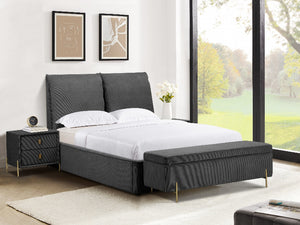 Grey upholstered bed with matching ottoman in a bright bedroom with large windows.