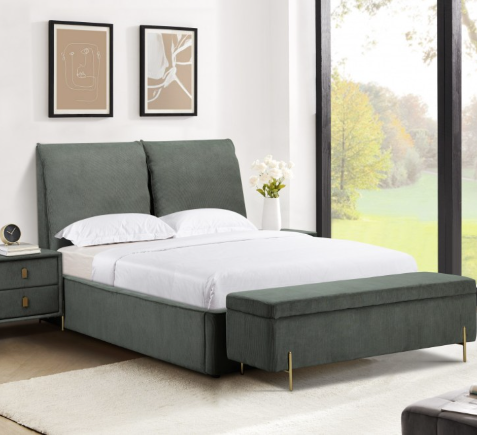 Gray upholstered bed with white bedding in a bright bedroom with large windows.