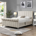 Beige upholstered bed in a bedroom with gray walls, white nightstands, and a rug.