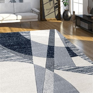 Geometric patterned rug on a wooden floor with a living room setting.