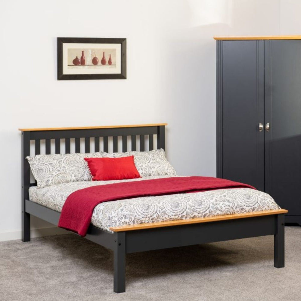 Bed with red blanket and gray headboard in a room with a wardrobe and framed picture on the wall.