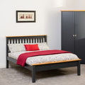Bed with red blanket and gray headboard in a room with a wardrobe and framed picture on the wall.