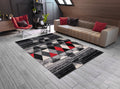 Living room with a geometric patterned rug, beige sofa, and red chair.