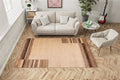 Living room with a beige sofa, small chair, and a patterned rug on wooden flooring.