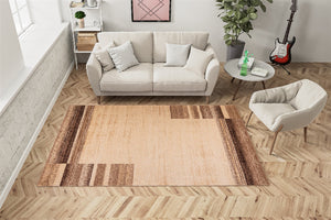 Living room with a beige sofa, small chair, and a patterned rug on wooden flooring.